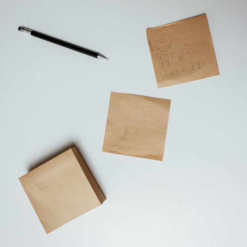 Top-down view of a minimalist setup with a pen and sticky notes on a white surface.